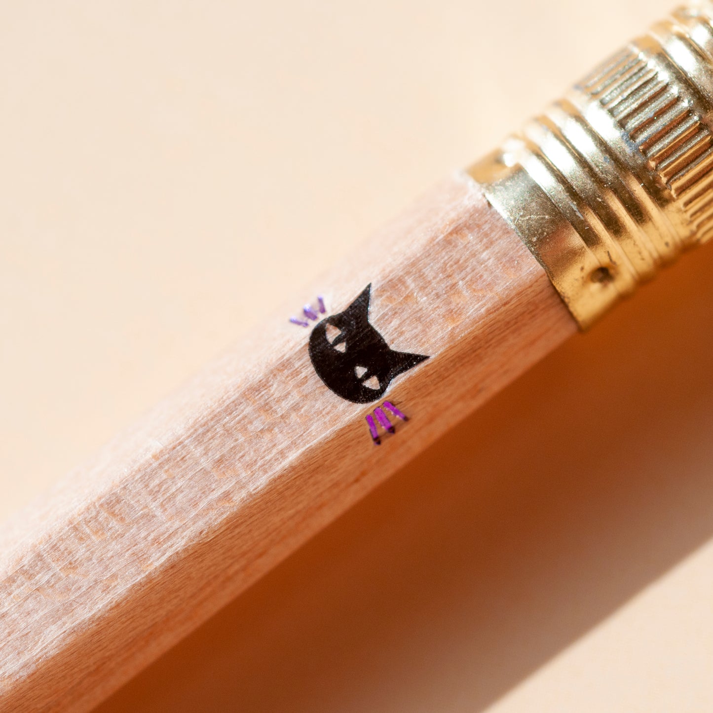 Macro shot of black cat face with purple whiskers, hot foil-stamped by hand on wooden pencils in Toronto