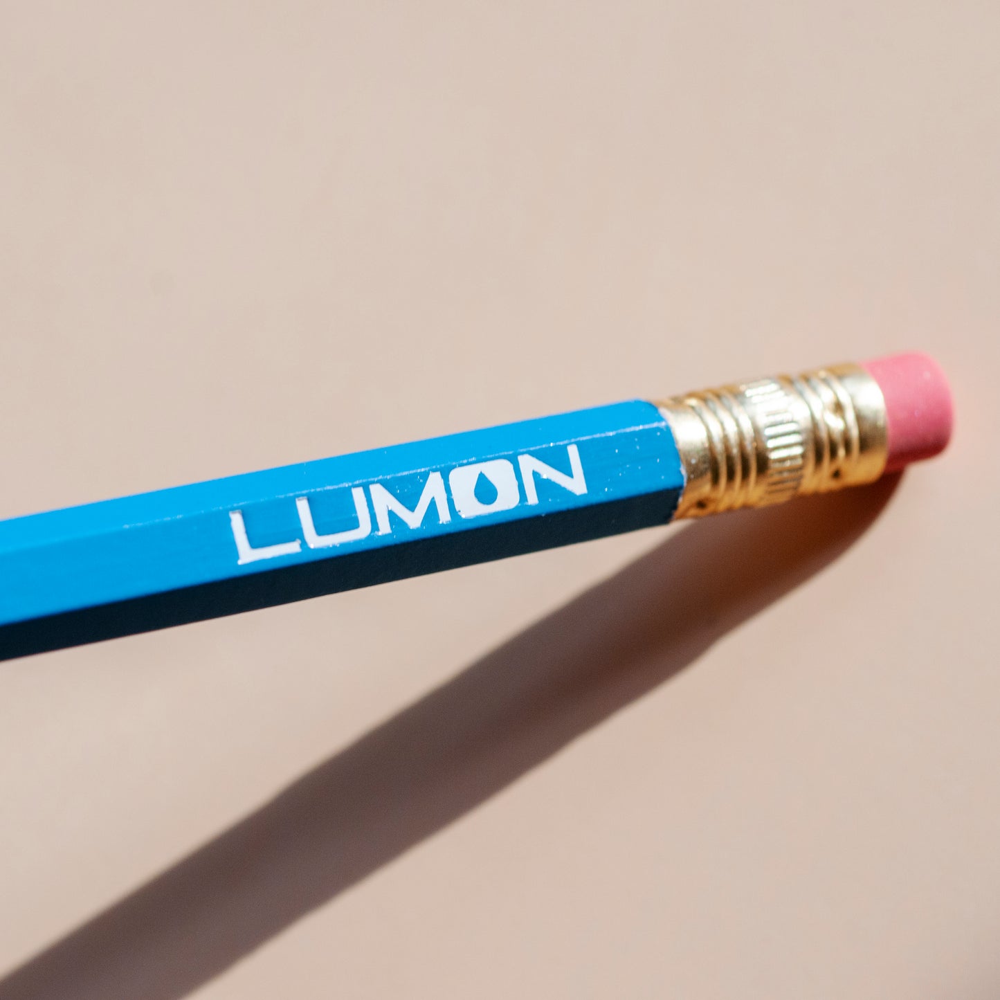 Macro shot of white Lumon logo stamped onto blue pencil, from Severance TV series