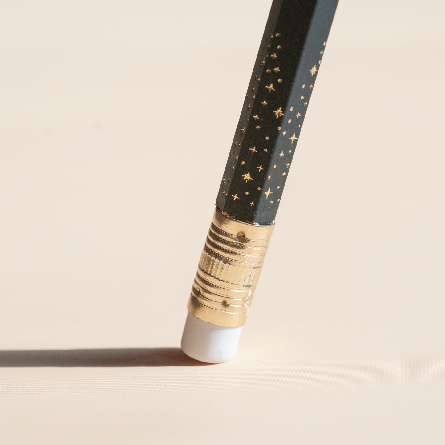 Macro shot of metallic gold stars design, hot foil-stamped onto matte black pencil