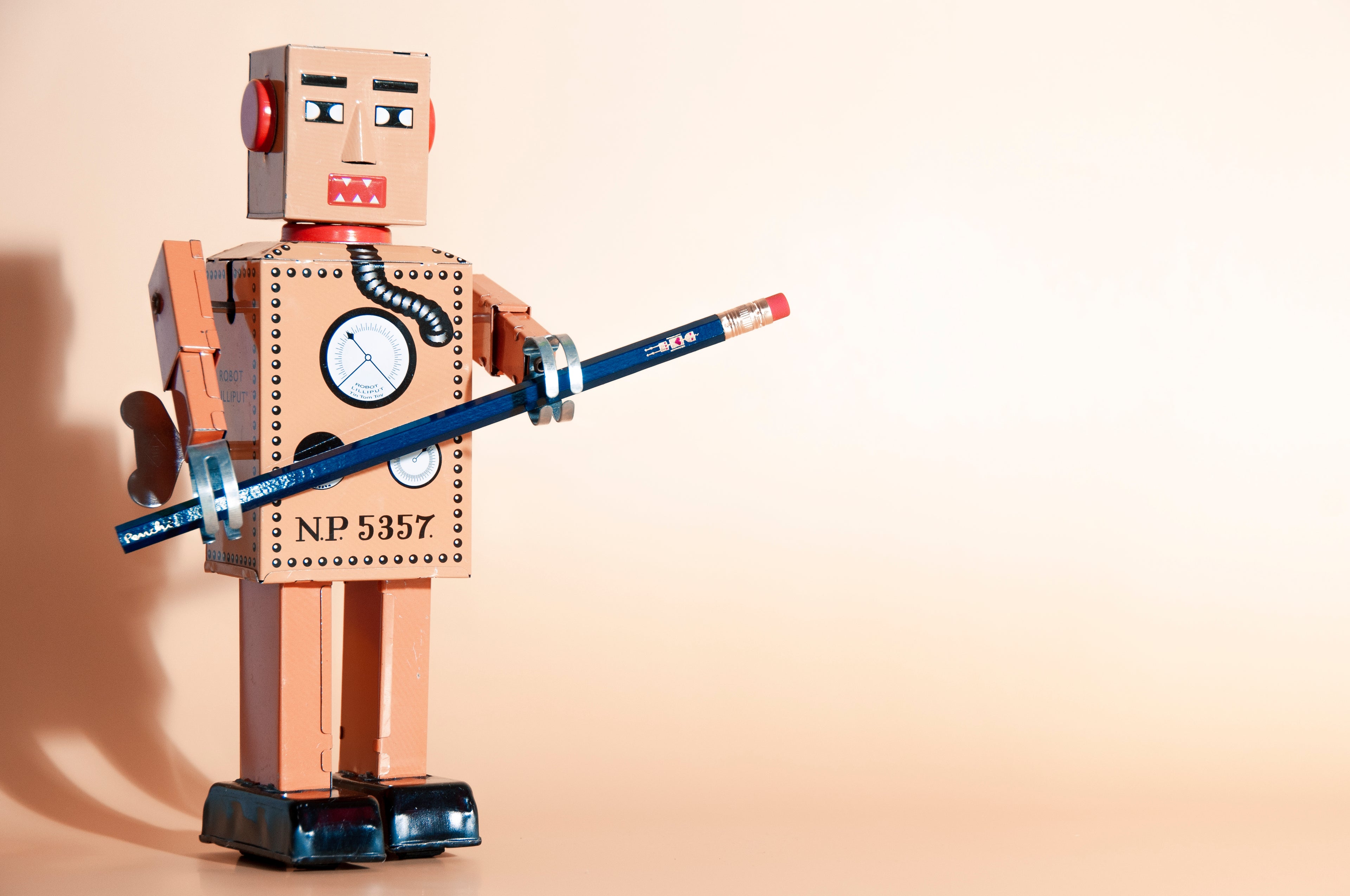 Lilliput Robot holding a wooden pencil with a tiny metallic robot stamped onto it by hand