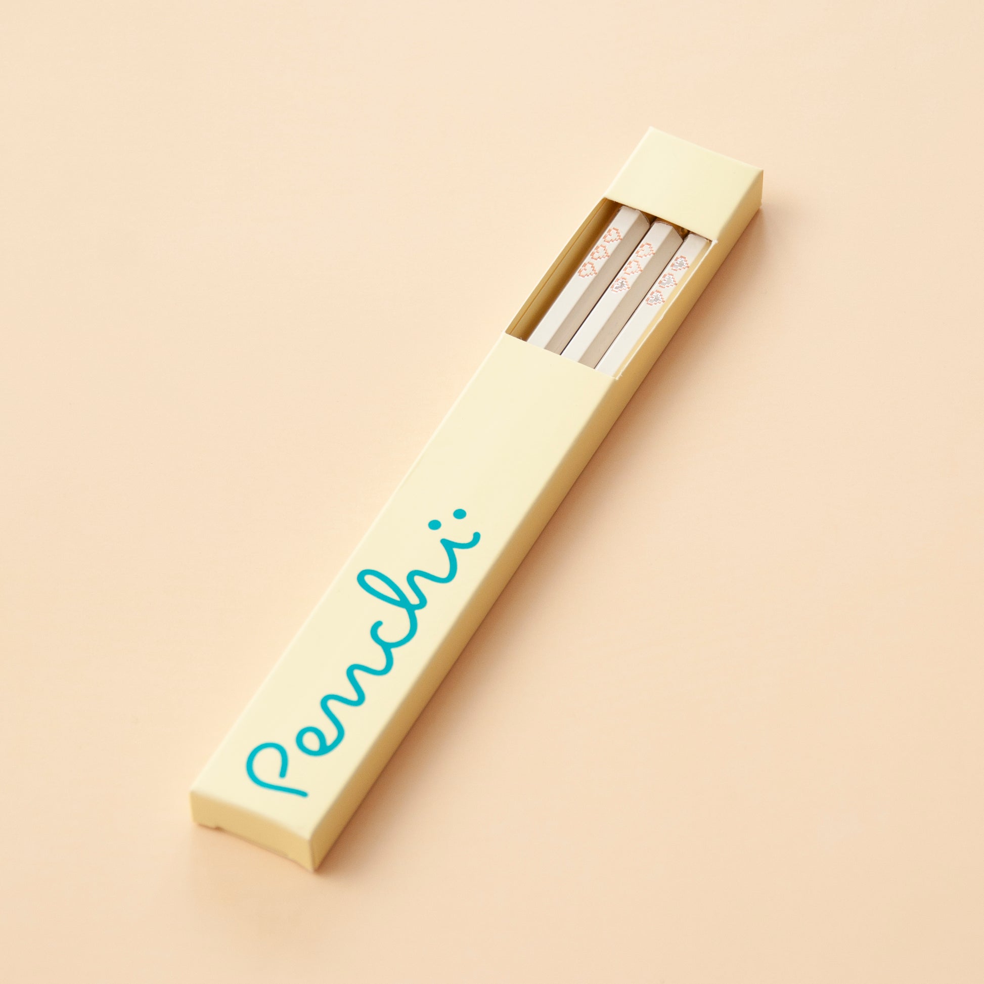 Handmade foil-stamped pencils with pixelated heart containers, packaged in yellow box with window and blue metallic foil