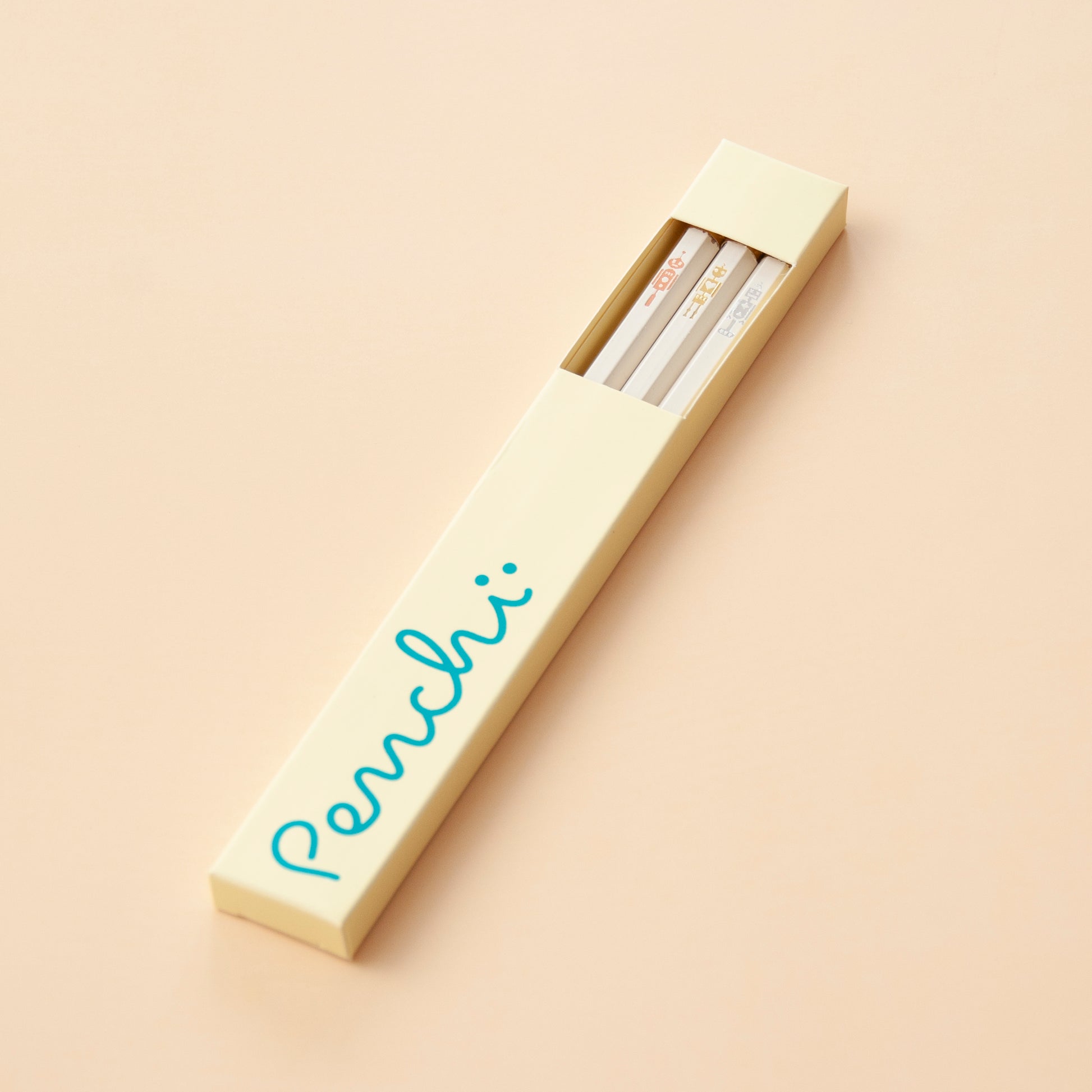 Pencil box packaging featuring a little window, holding the Penchi Robots pencil set inside, neutral shades