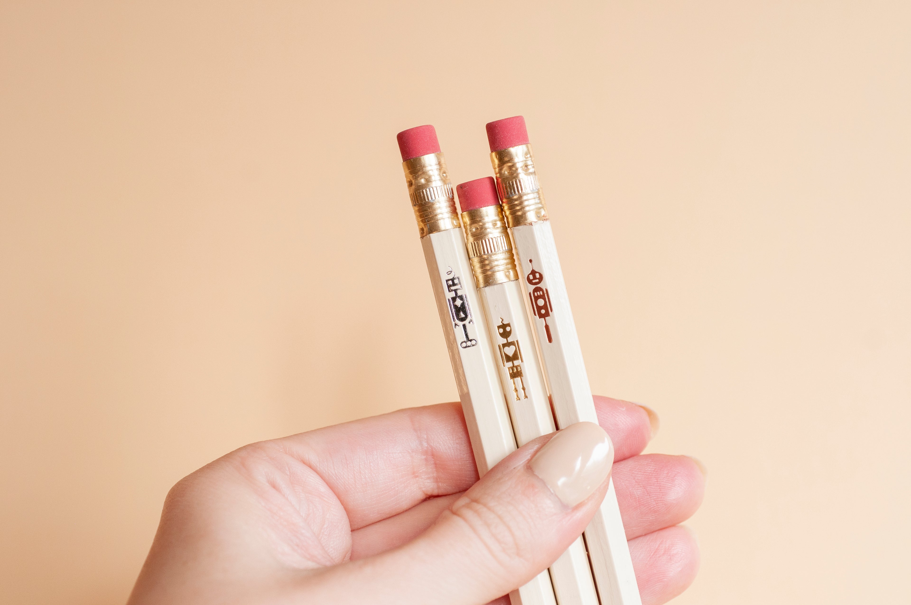 Tiny shiny metallic robots hot-stamped onto wooden pencils, made with silver, gold, and copper foils